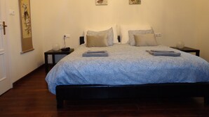 A bedroom with a large bed, two nightstands, a wall-mounted lamp, and two framed artworks. - Family-friendly holiday home with heated swimming pool for 11 people + 2 baby's (Poroszló)