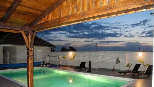 An indoor swimming pool with a wooden ceiling, tiled floor, and a view of the sky. - Family-friendly holiday home with heated swimming pool for 11 people + 2 baby's (Poroszló)
