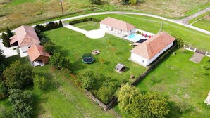 An aerial view of a residential property with two houses, a swimming pool, and a trampoline. - Family-friendly holiday home with heated swimming pool for 11 people + 2 baby's (Poroszló)