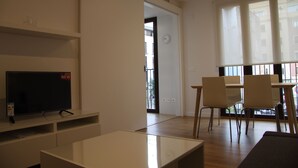 A modern living room with a flat-screen TV, a coffee table, and a dining area with chairs and a table. - Fantastic new apartment in the center of town. (València)