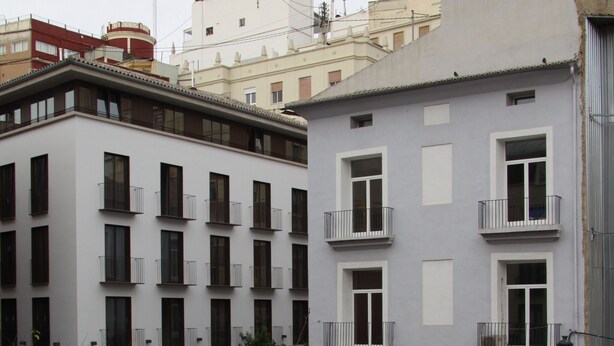 A multi-story building with balconies, a courtyard with benches, and a street in the background. - Fantastic new apartment in the center of town. (València)