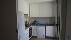 A compact kitchen with white cabinets, a dishwasher, and a countertop with a blue dish rack. - Fantastic new apartment in the center of town. (València)