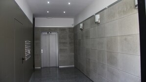 A modern elevator with a metallic finish, a grey tiled wall, and a door with a handle. - Fantastic new apartment in the center of town. (València)