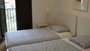 A room with two beds, a window, and a door leading outside. - Fantastic new apartment in the center of town. (València)