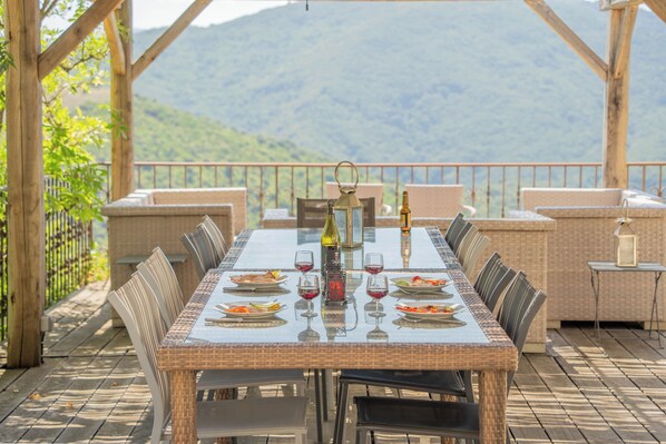 A dining table set for six with chairs, a bottle of wine, and a candle holder.