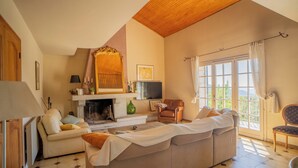 A living room with a fireplace, a sofa, a television, and a large window with curtains. - Mansion - SORBOLLANO (Sorbollano)