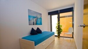 Een slaapkamer met een bed, een stoel, een potplant en een schilderij aan de muur.