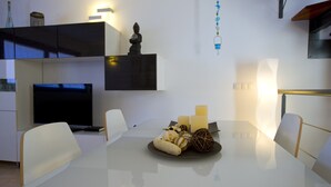 Een moderne eethoek met een witte tafel, stoelen, kaarsen en decoratieve objecten.