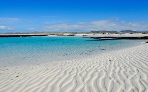 Ein Strand mit klarem türkisblauem Wasser und weißem Sand.