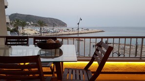 A table with chairs and a view of a beach and marina.