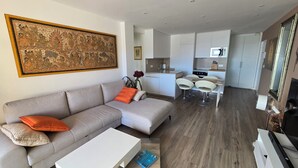 En moderne stue med en grå sofa, et hvidt sofabord og et stort billede med ramme på væggen.