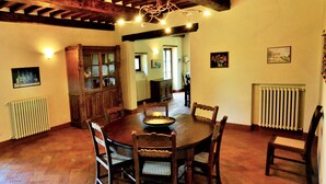 Un comedor con una mesa y sillas de madera, una araña y un techo rústico.