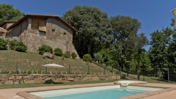 Une piscine avec une maison en pierre en arrière-plan.