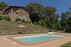 Una piscina con una casa de piedra al fondo.