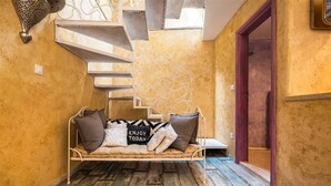 A cozy seating area with a cushioned bench, a decorative wall piece, and a staircase leading to an upper level. - Nicely decorated Casablanca suite with terrace, Wifi, sauna and bikes ... (Veli Lošinj)