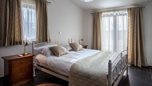 A bedroom with a bed, nightstands, a lamp, curtains, and an air conditioning unit. - Villa Torine ZadarVillas (Zapužane)