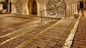 Un bâtiment historique doté d’une façade à la texture particulière, de portes en arc de cercle et d’un escalier menant à l’entrée.