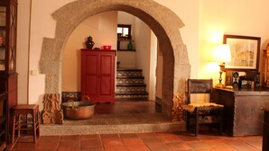 A stone archway leading to a staircase, wooden furniture, and a lamp. - House with garden in Óbidos Castle (Óbidos)
