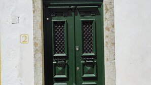 A green door with a small window above it, set in a white and yellow building. - House with garden in Óbidos Castle (Óbidos)