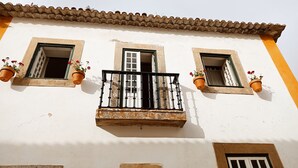 A building with three windows, each with a balcony and potted plants. - House with garden in Óbidos Castle (Óbidos)