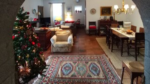 A cozy living room with a Christmas tree, a patterned rug, and a dining area with a chandelier. - House with garden in Óbidos Castle (Óbidos)