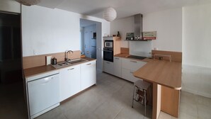 A modern kitchen with white cabinetry, a wooden countertop, a built-in oven, and a hanging light fixture. - Fouras, Villa with character, direct private access to the beach. (Fouras)