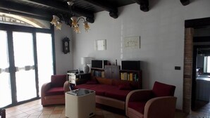 Una sala de estar con sofá, sillones, una mesa de centro y un mueble de televisión con libros.