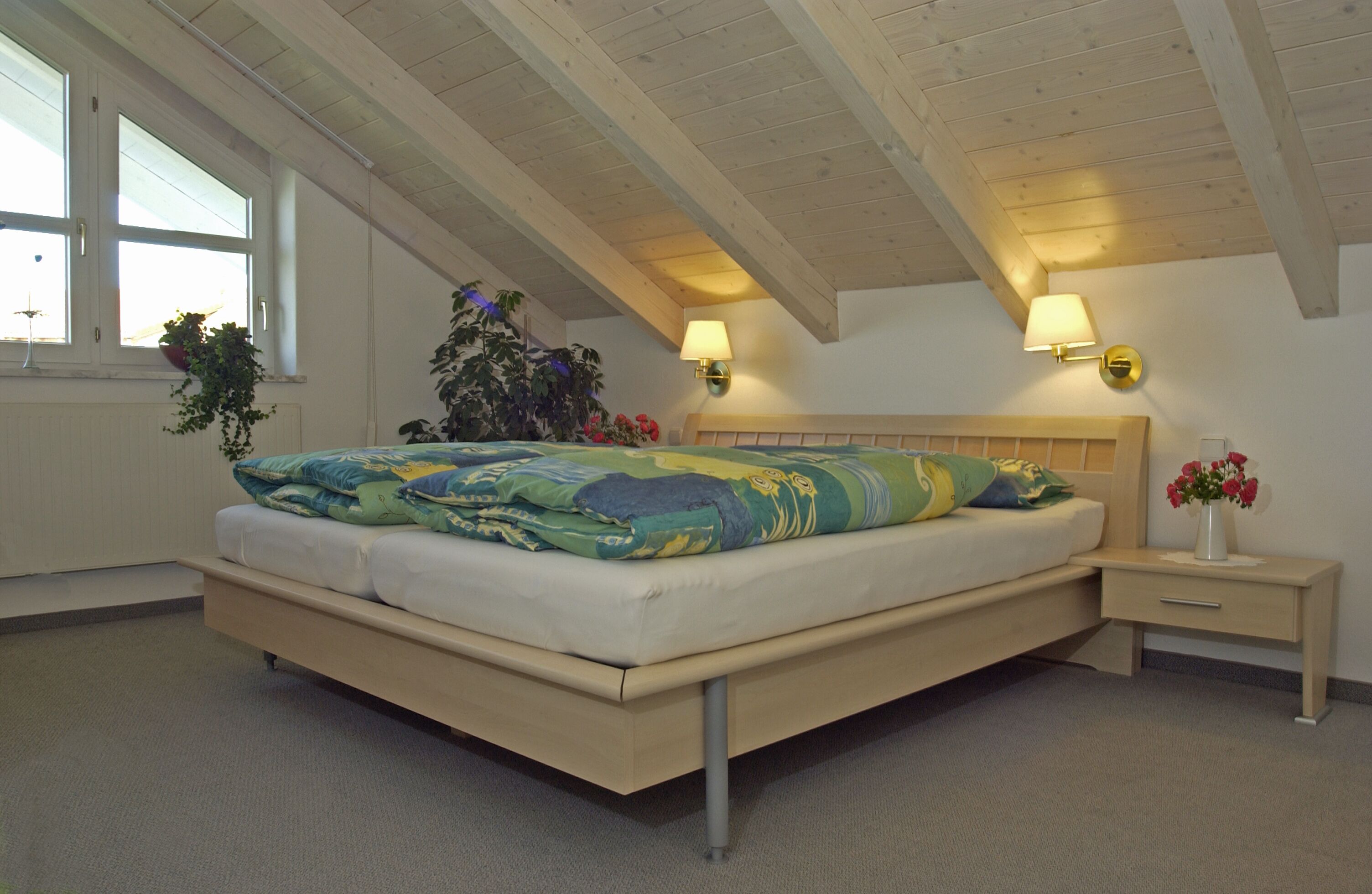 Ein Schlafzimmer mit einem Bett, Nachttischlampen, einem Nachttisch und einem Blumentopf.