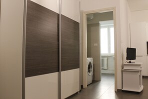 Un espace buanderie comprenant un lave-linge, un sèche-linge et un téléviseur posé sur un meuble.
