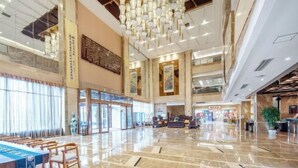 Un hall d’entrée spacieux avec un plafond haut, un lustre et un comptoir d’accueil.