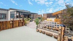 Un espace extérieur doté d’un bâtiment moderne, d’une clôture en bois et de différents types de mobilier d’extérieur.