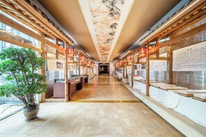 A corridor with wooden beams, a potted plant, and informational displays on the walls.