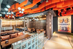 A modern restaurant interior with seating arrangements, a bar area, and a prominent beer advertisement.