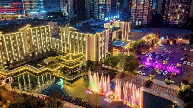 Un hôtel à étages, doté d’un parking et d’une fontaine illuminée de lumières colorées.