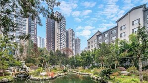 A residential area with a pond, trees, and modern buildings. - Emeishan Yue Garden Hotel (Jiajiang)