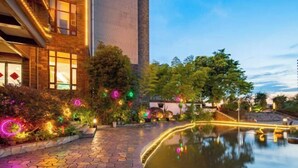 Une cour d’hôtel avec une piscine aux eaux miroitantes, un bâtiment en briques et des éclairages décoratifs.