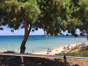 A beach with clear turquoise water, people sunbathing, and umbrellas.
