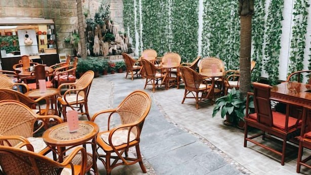 An outdoor café with wicker furniture and a stone wall backdrop. - Hongqi Hotel (Datong)