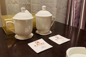 Two white ceramic teapots with lids on a dark countertop, accompanied by two white napkins with text.