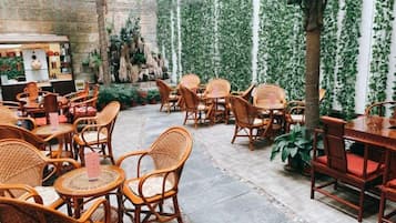 Een terras met rieten meubels en een stenen vloer.
