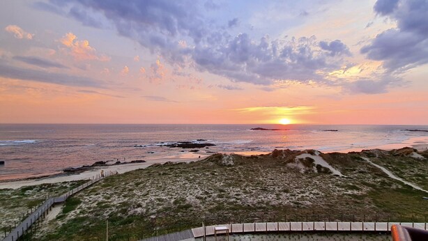 A coastal landscape with a sunset, sandy beach, and dunes. - Beachfront Apartment - By the SEA (Vila do Conde)