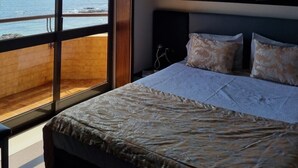 A bedroom with a large bed, a view of the sea through a sliding door, and a wall clock. - Beachfront Apartment - By the SEA (Vila do Conde)