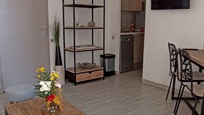 Ett modernt vardagsrum med ett soffbord i trä, en gul pall, en bokhylla och en matplats med stolar.