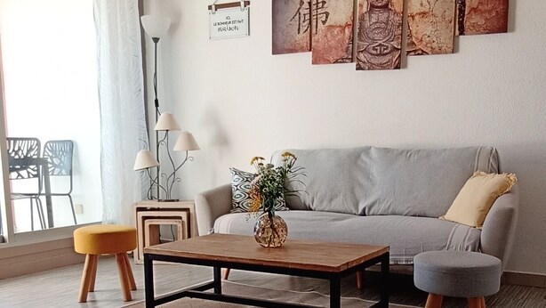 Ett modernt vardagsrum med en grå soffa, ett träbord och en hängande lampa.