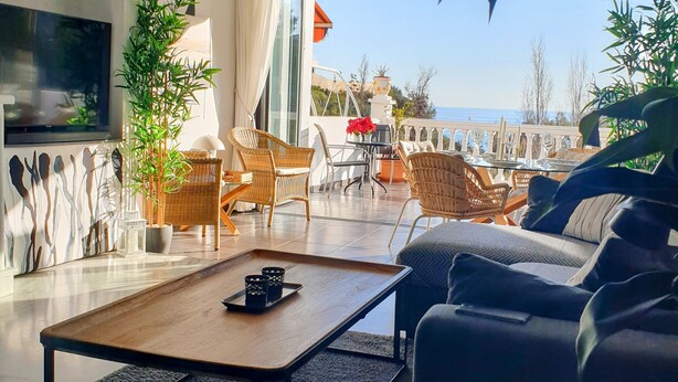Ein modernes Wohnzimmer mit einem großen Fenster und Blick auf eine malerische Aussicht, ausgestattet mit einer Couch, Sesseln und einem Couchtisch.