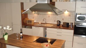A modern kitchen with a wooden countertop, built-in appliances, and a stainless steel range hood. - Sunny, spacious & fully equipped, castle views, close to lake/beach, restaurants (Schwangau)