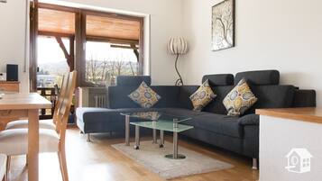 Ein modernes Wohnzimmer mit einer Couch, einem Couchtisch und einem Essbereich mit Stühlen.