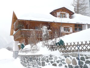 Een houten chalet met een stenen muur, omgeven door sneeuw.