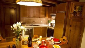 A wooden kitchen with a dining table set for two, featuring a vase of flowers, a candle, and various dishes. - San Vito: Beautiful apartment a stone's throw from Cortina d 'Ampezzo (San Vito di Cadore)