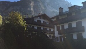 A mountain with a clear sky. There are buildings with balconies and a stone wall in the foreground. - San Vito: Beautiful apartment a stone's throw from Cortina d 'Ampezzo (San Vito di Cadore)
